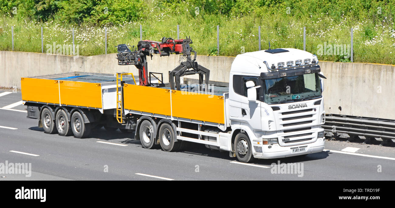Front & side view Scania hgv truck towing trailer loaded paving bricks building materials lorry has crane to offload at delivery site seen UK motorway Stock Photo