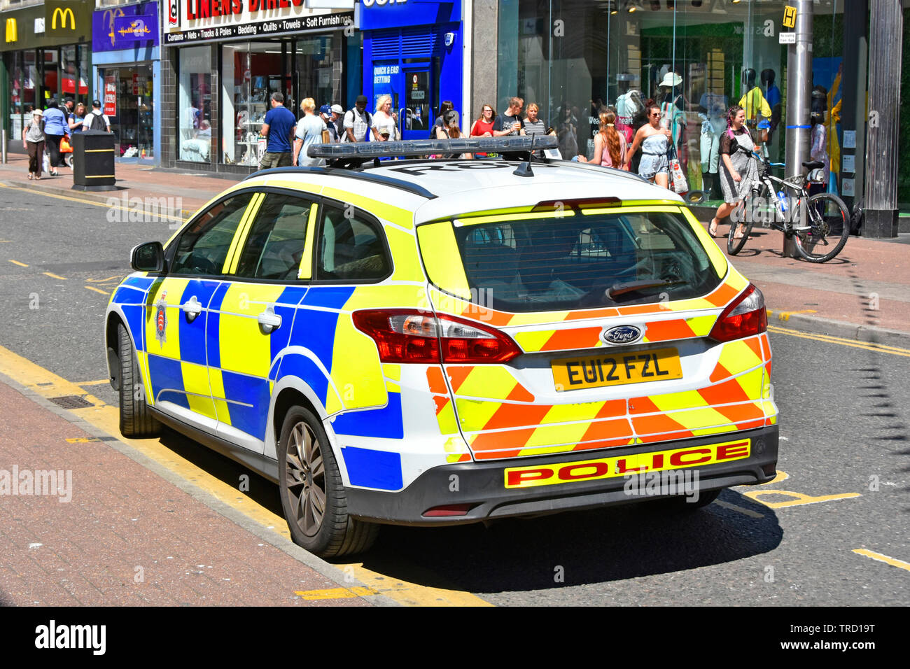 Shoppers in busy high street Essex police force patrol car high visibility markings in town centre shopping area in Southend on Sea  Essex England UK Stock Photo