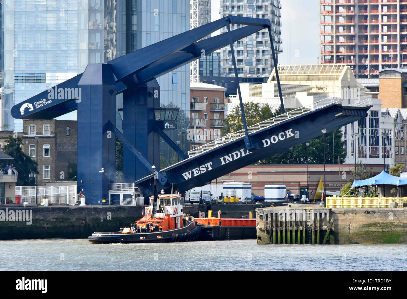 Entrance for tug boat to South Dock of West India Docks access to Canary Wharf estate via River Thames & raised modern road bridge London Docklands UK Stock Photo