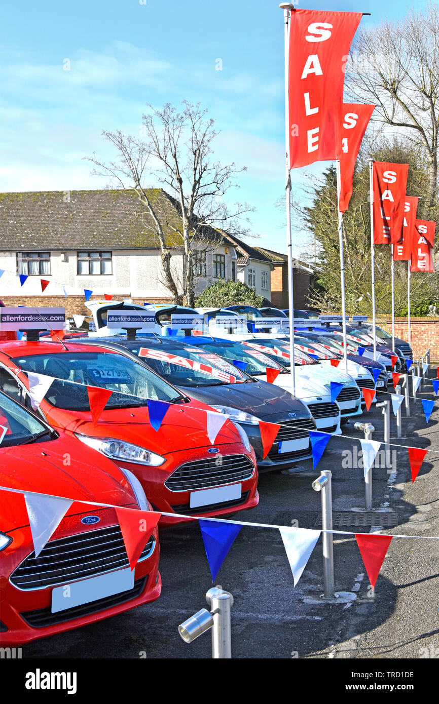 Sale poster at Ford car dealership business on forecourt display used second hand red white & blue cars bunting & sales promotion banners England UK Stock Photo