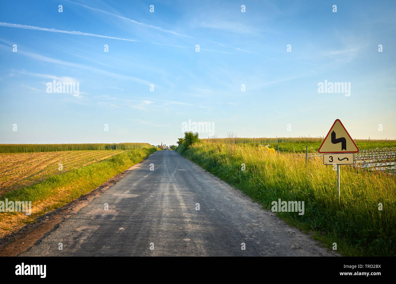 Picture of a country road with dangerous bends traffic sign at sunset. Stock Photo