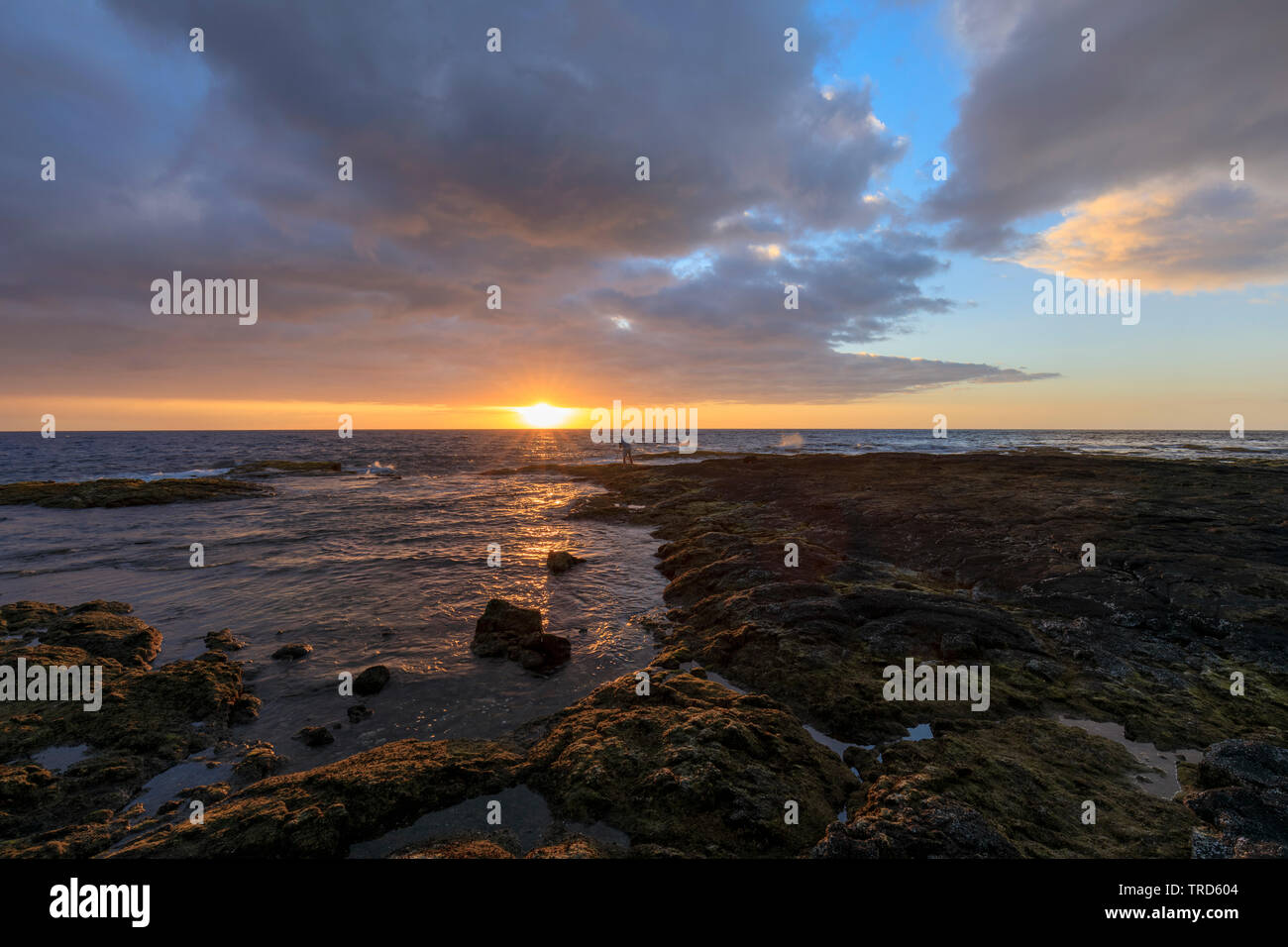 Photographer (model released) on Palemano Point in Keei, South Kona, Hawaii takes ocean sunset photo Stock Photo
