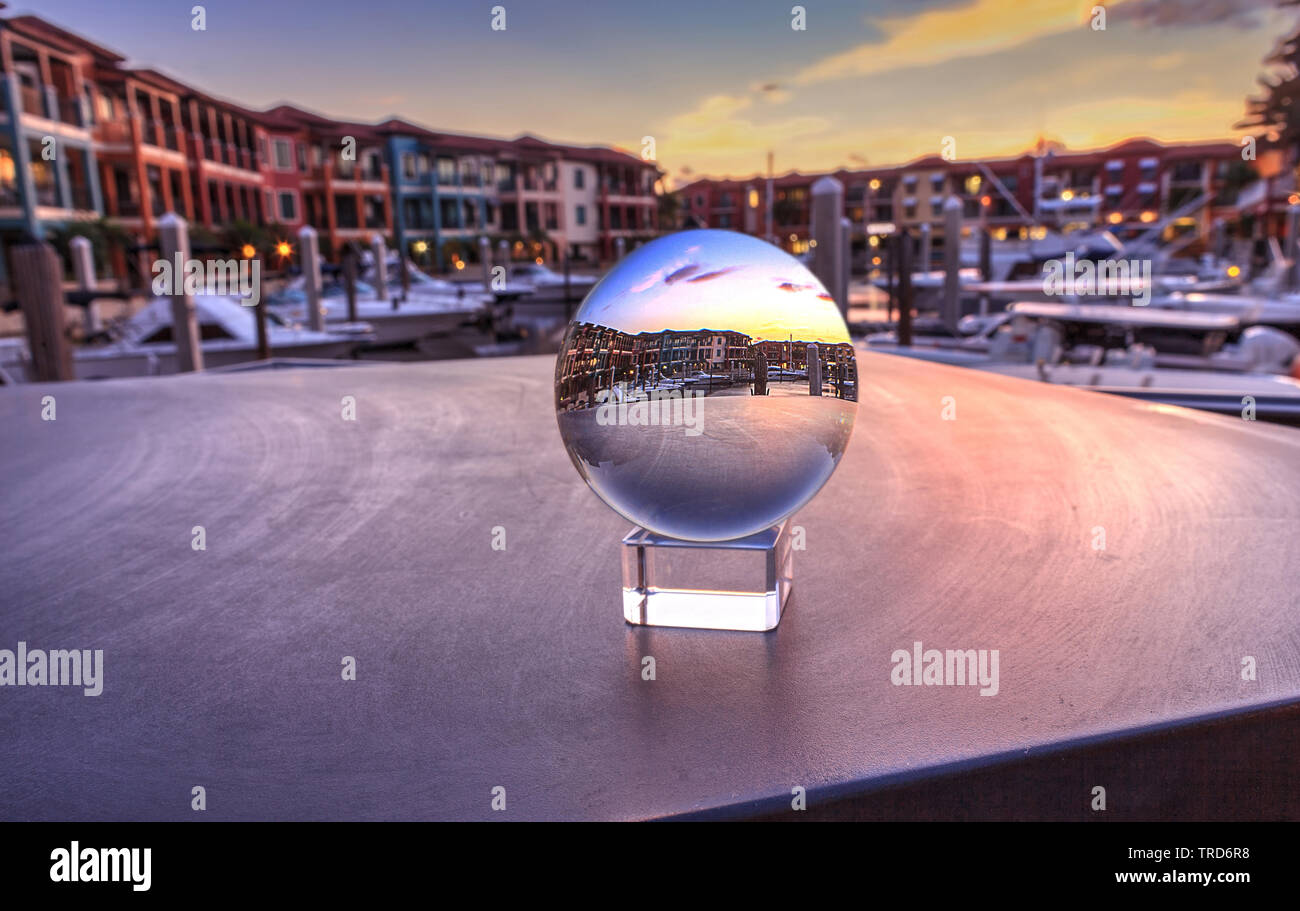 Naples, Florida, USA – May 29, 2019: Crystal ball with colorful buildings and a harbor of boats along a waterway in Naples, Florida inside. Stock Photo