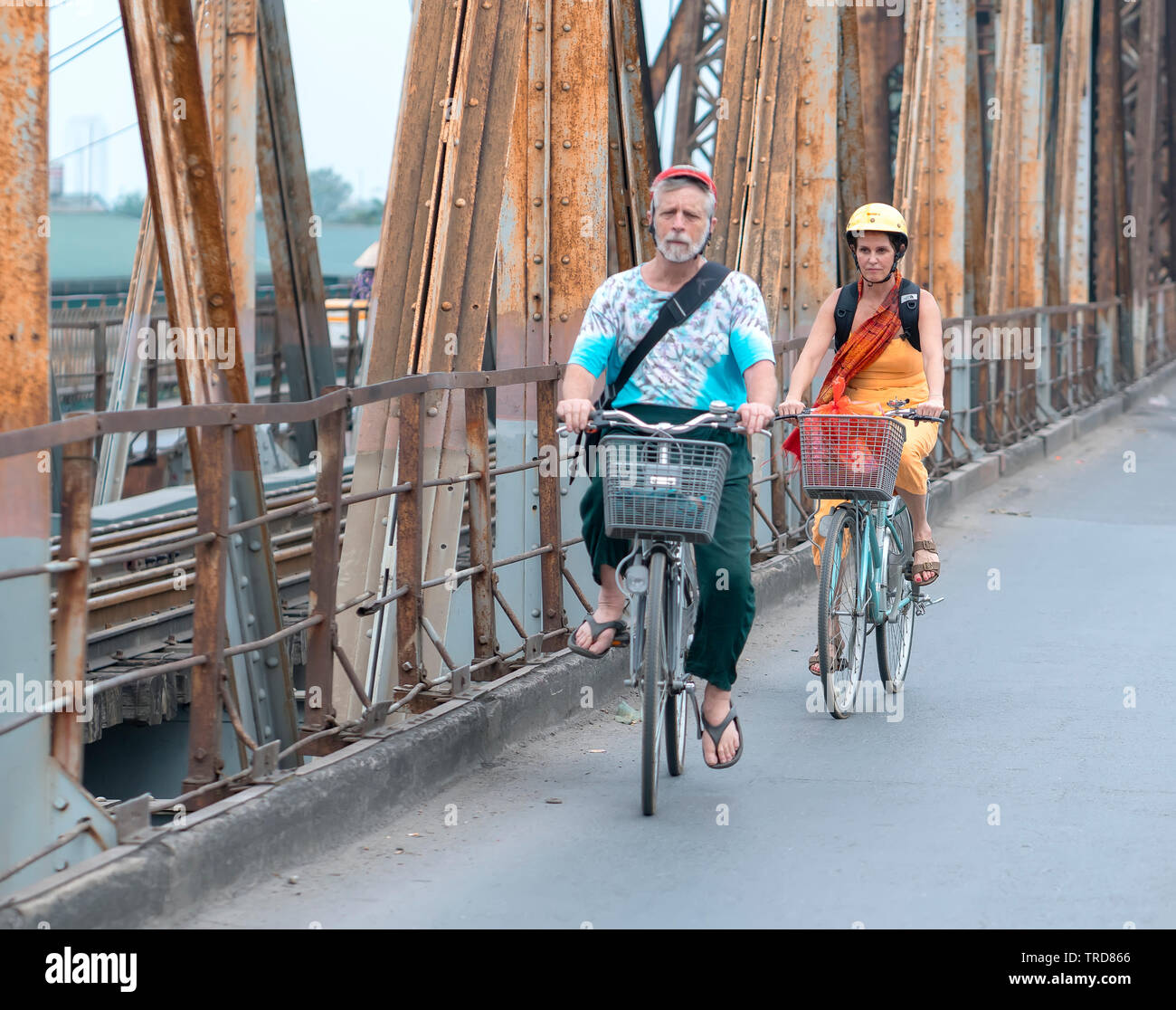 Couples riding a bicycle together on railroad tracks leading over Long