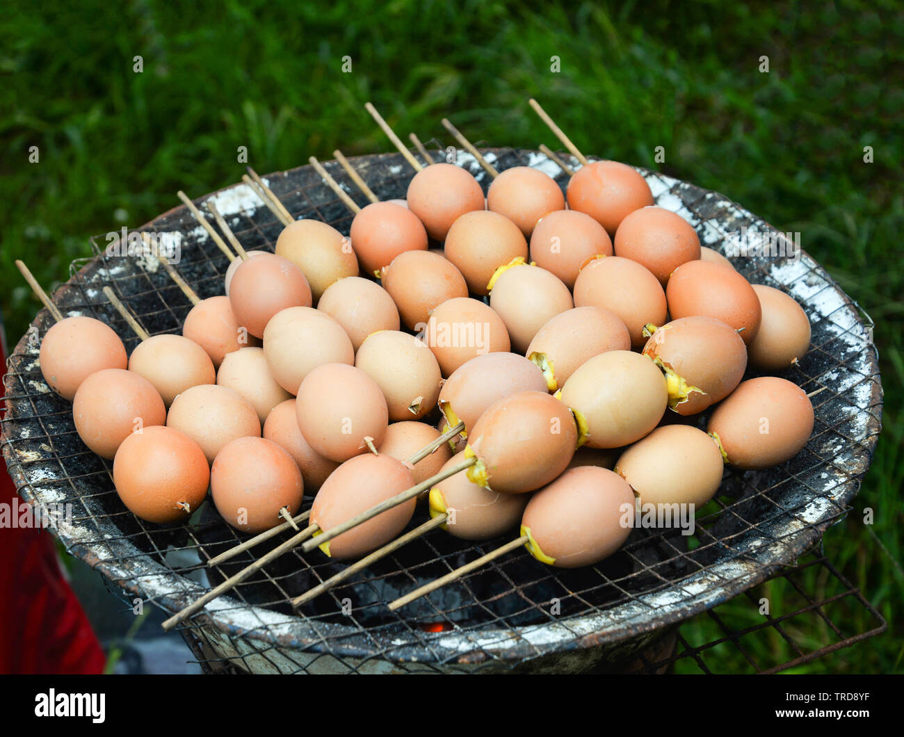 Eggs grilled with bamboo stick on grill hot stove in street food market