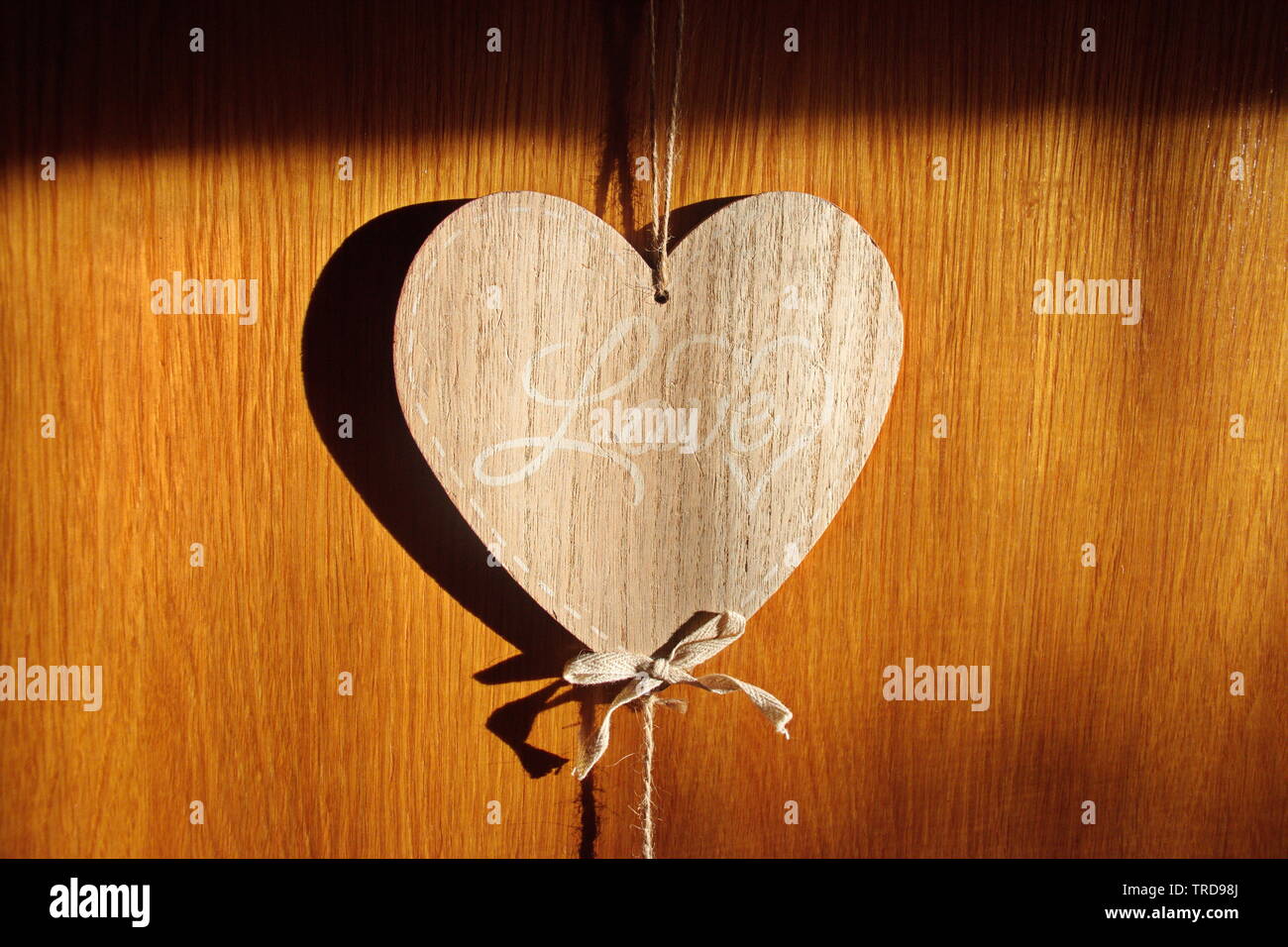 Wooden heart shape with text Love hanging on the wooden background Stock Photo