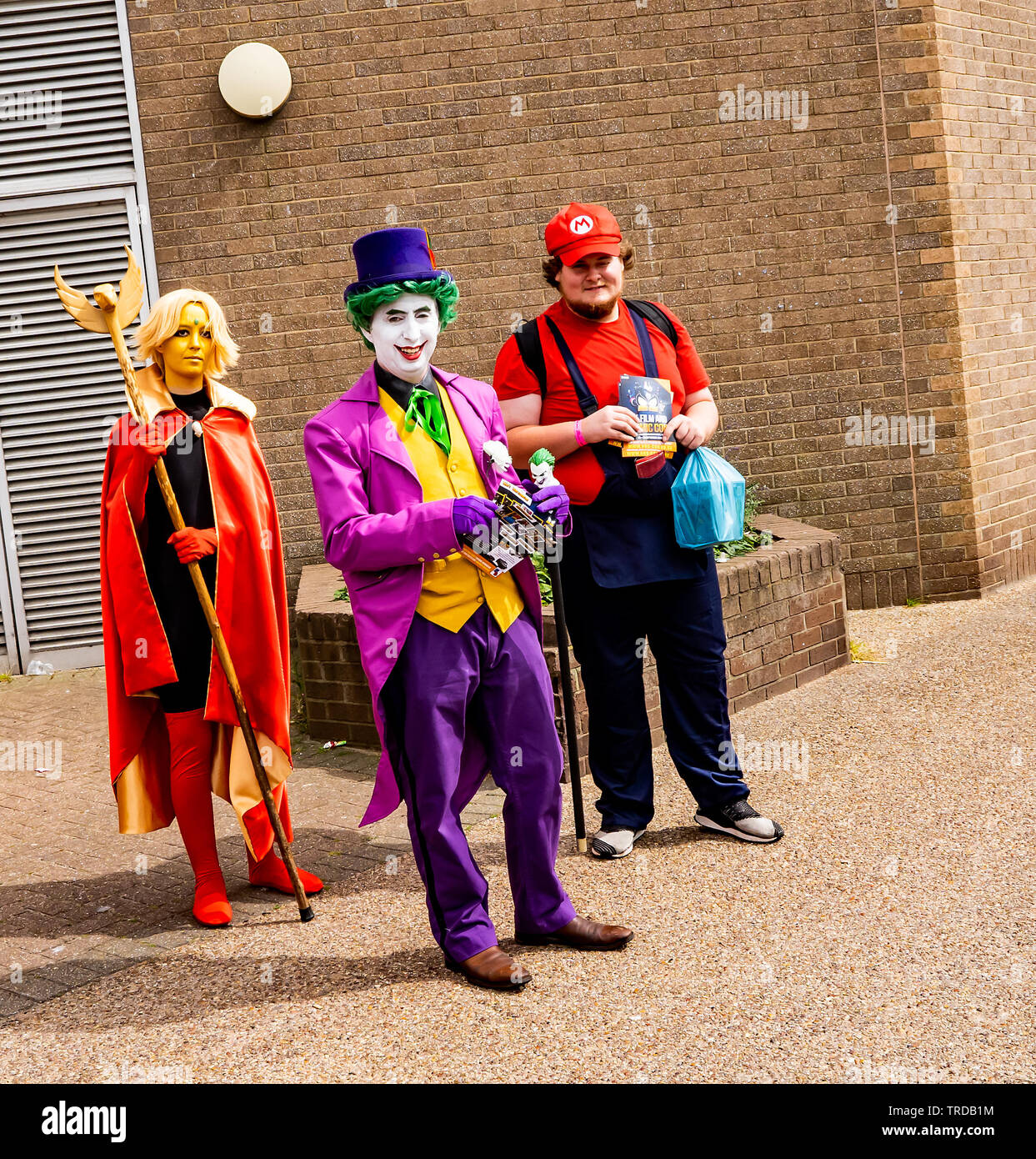 Great Yarmouth Comicon 2019 – The Joker, Mario and a super heroine outside the entrance of the Comicon event in the seaside town of Great Yarmouth Stock Photo