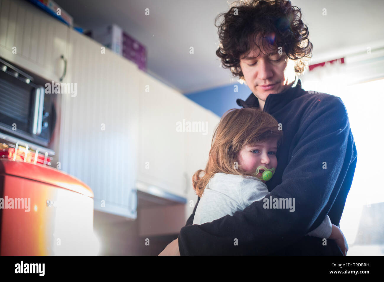 Young dad and toddler baby girl embracing at home in natural morning light. Stock Photo