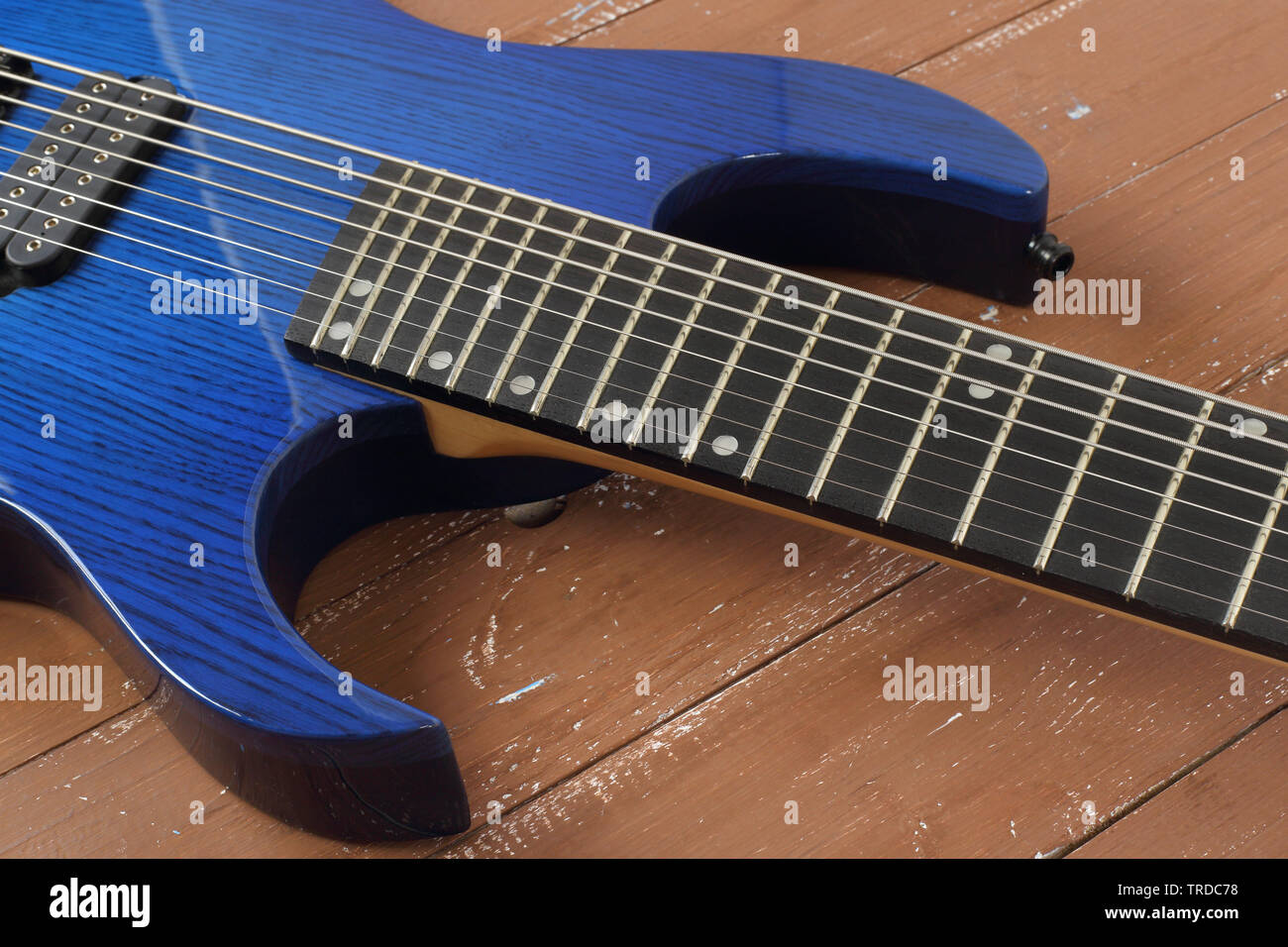 Musical instrument - Fragment 8-string blue electric guitar solid-body on a wood background Stock Photo