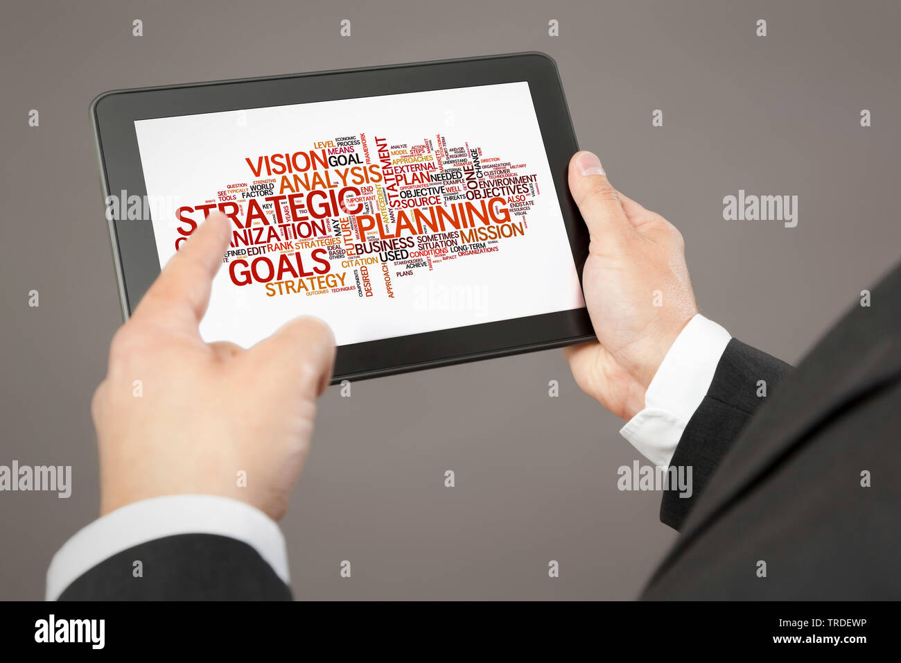 Close-up view of hands holding a tablet showing a tag cloud about strategy Stock Photo
