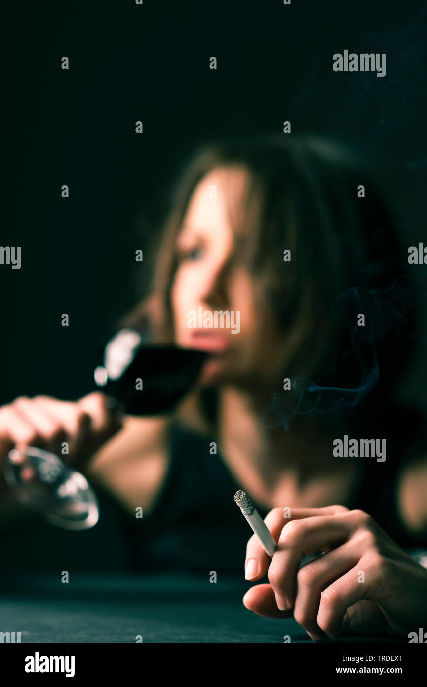 Portrait of a depressed drunken woman with a glass of wine and a cigarette in her hands Stock Photo