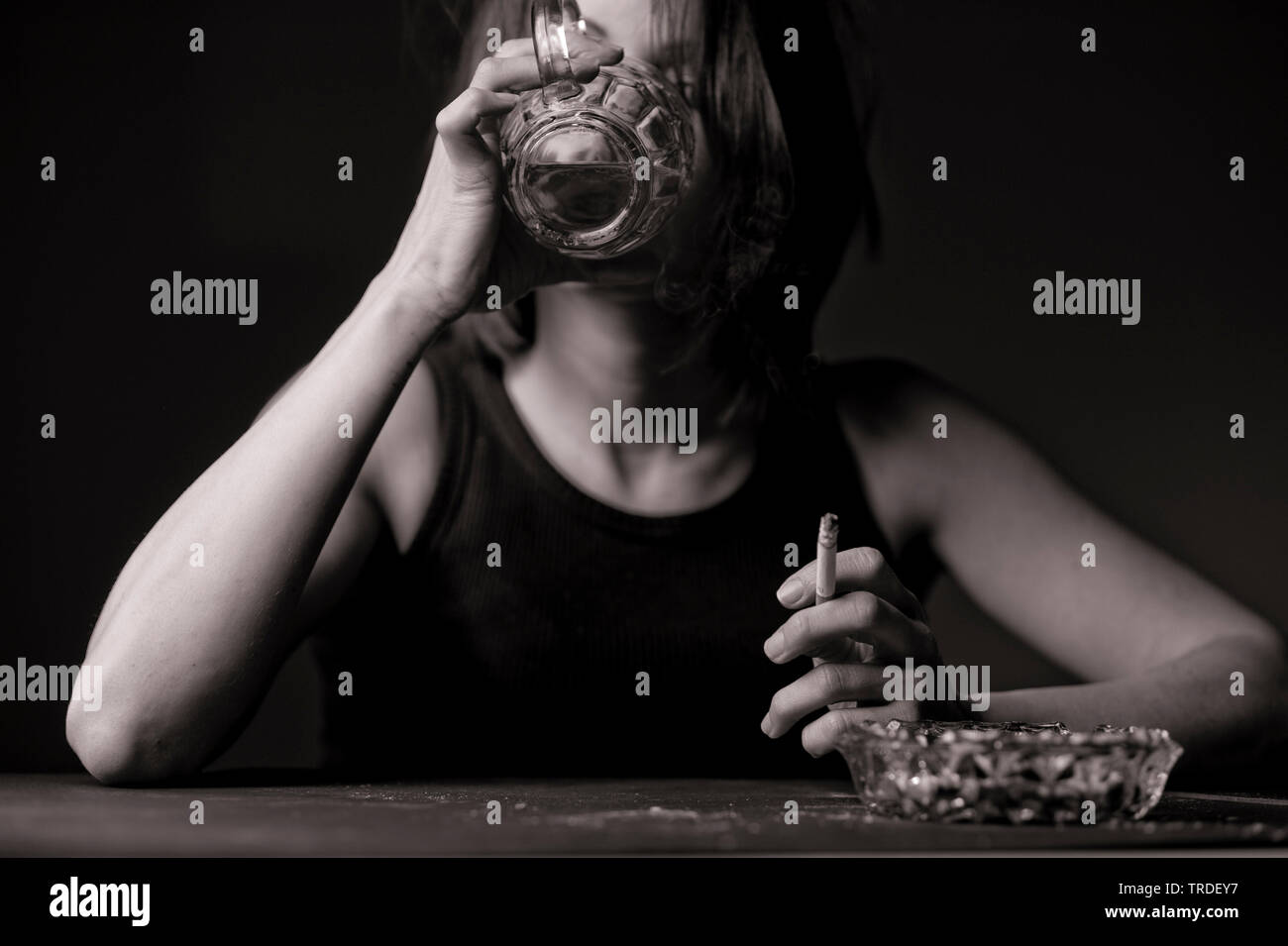 Black/White portrait of a depressed and alcoholised woman with a glass of  beer and a cigarette in her hands Stock Photo