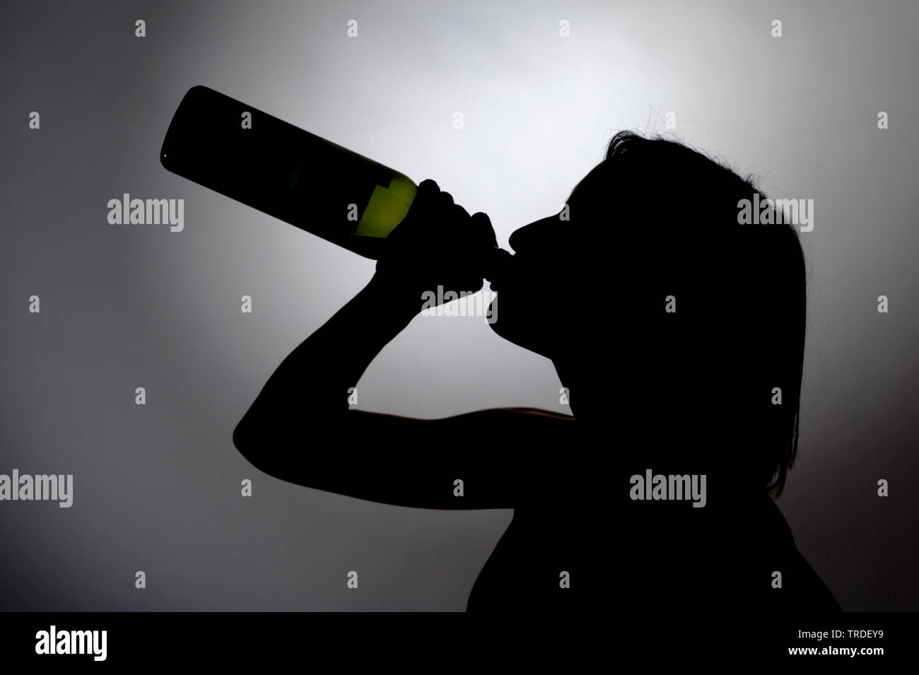 Black/White silhouette of a young woman drinking out of a bottle of wine Stock Photo