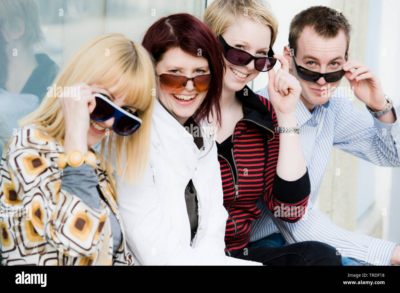 Group portrait/side view of 4 young persons wearing sunglasses sitting ...