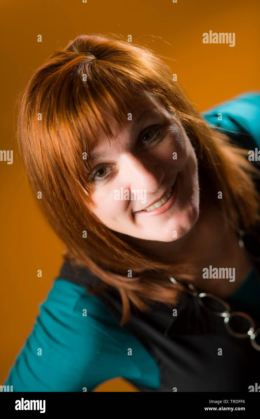 Portrait of a likeable middle aged woman with red hair against brown background Stock Photo