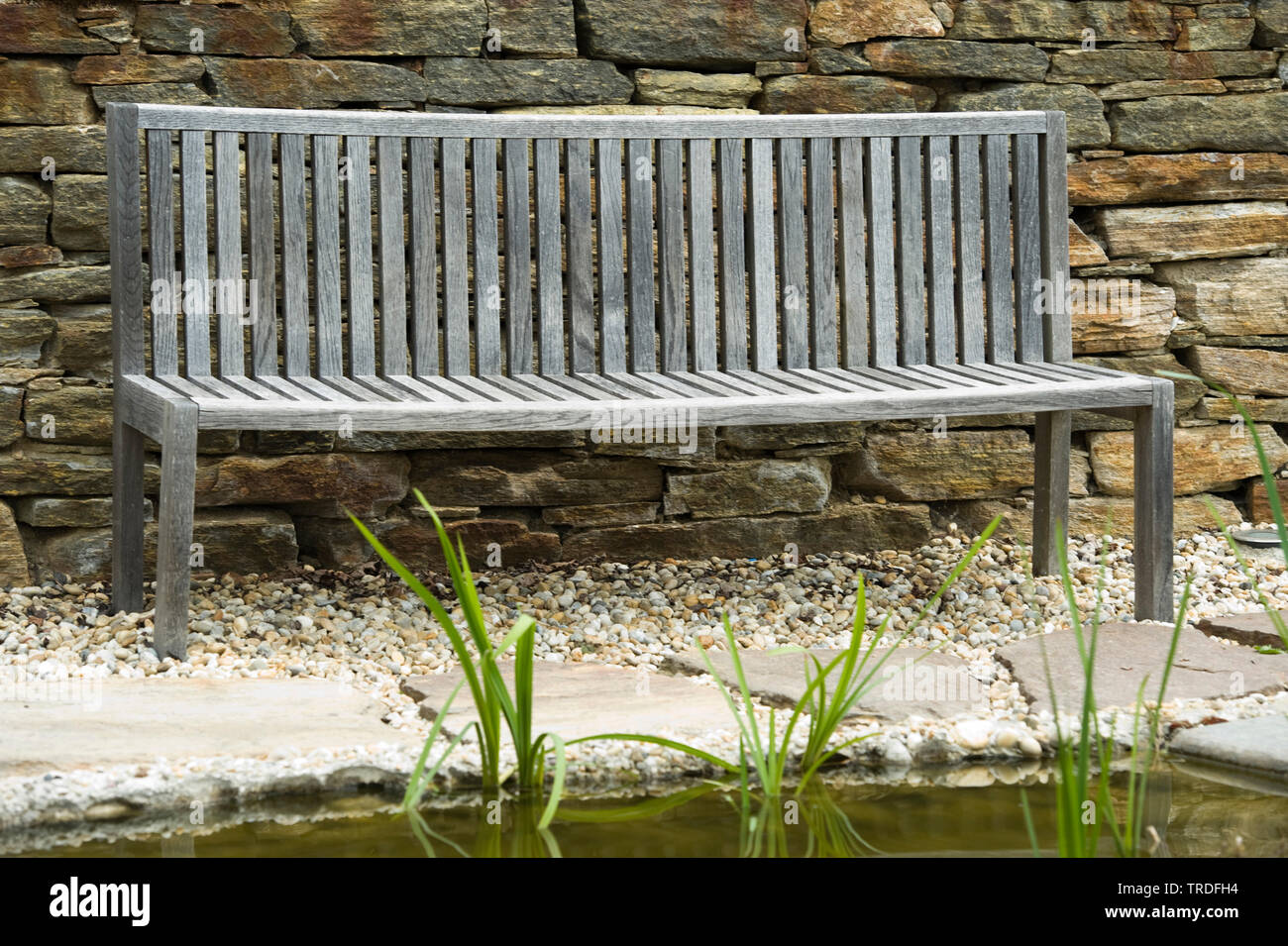 Empty wooden bench in front of a stone wall Stock Photo