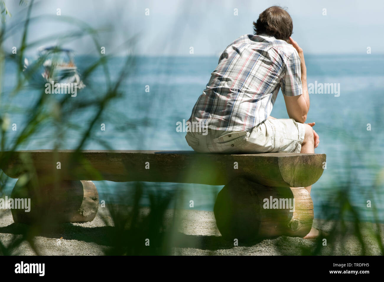 Portrait of a thoughtful man sitting on a bench in front of a lake, Germany, Baden-Wuerttemberg Stock Photo