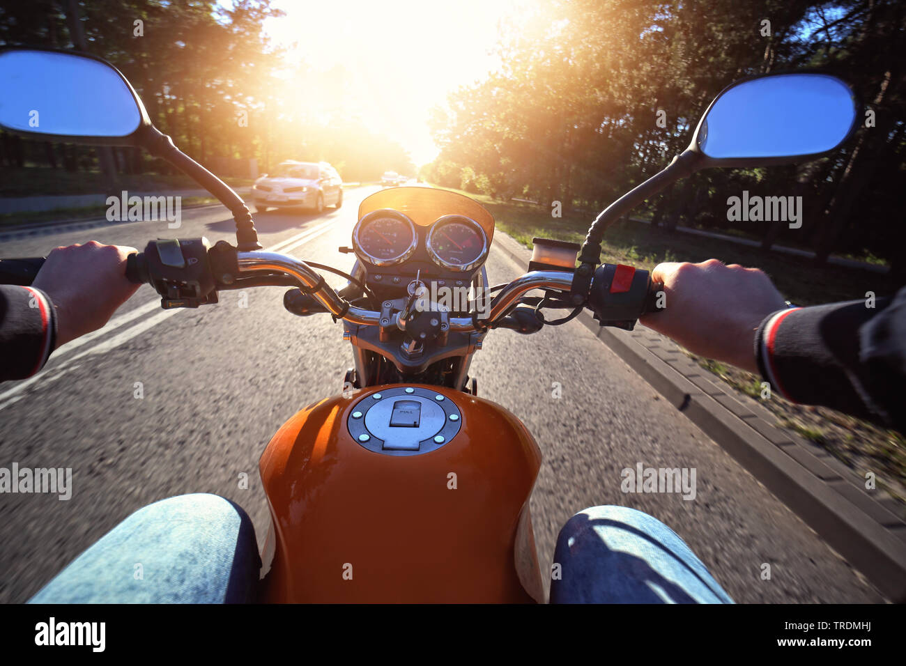 Motorcyclist drives motorbike on a sunny day on the street Stock Photo