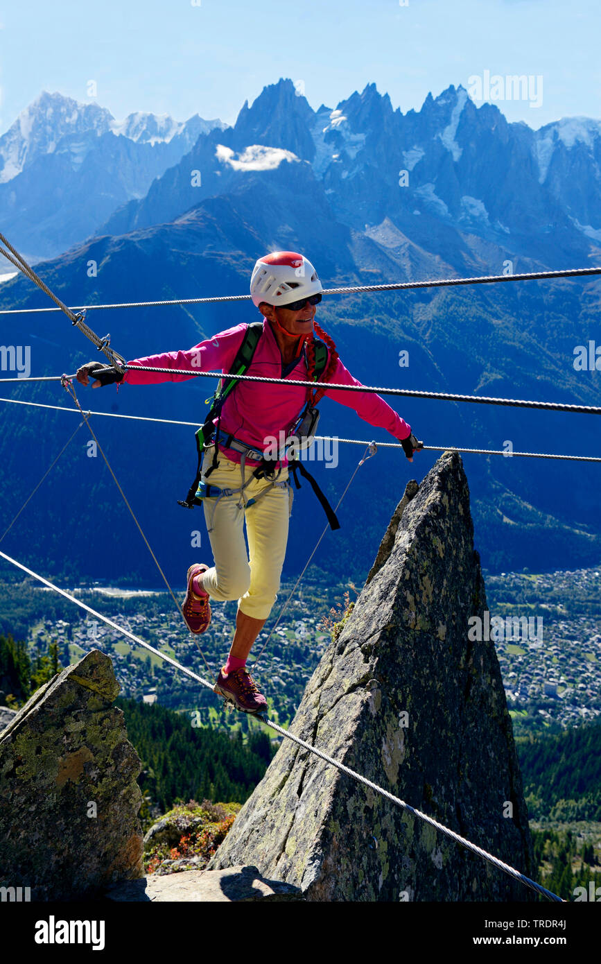 woman balancing on a tightrope, Via ferrata des Evettes, France, Savoie Stock Photo