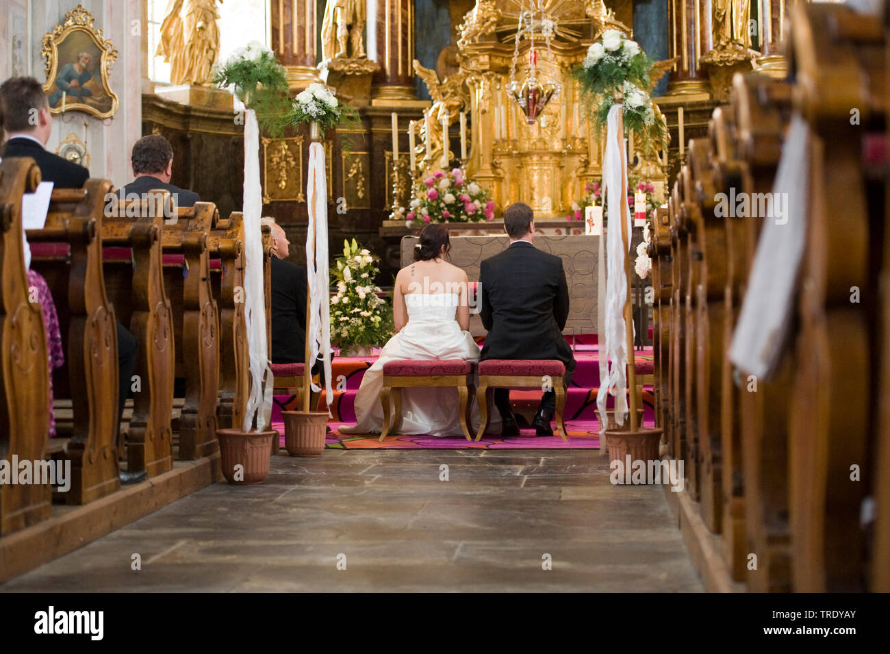 Rear view of a bridal couple sitting in the church in front of teh altar Stock Photo