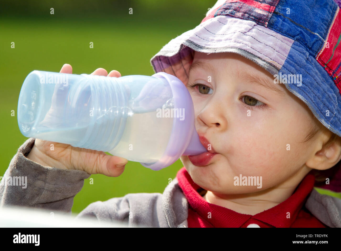 Head-shoulder portrait of a young boy outdoors drinking out of a teat bottle Stock Photo