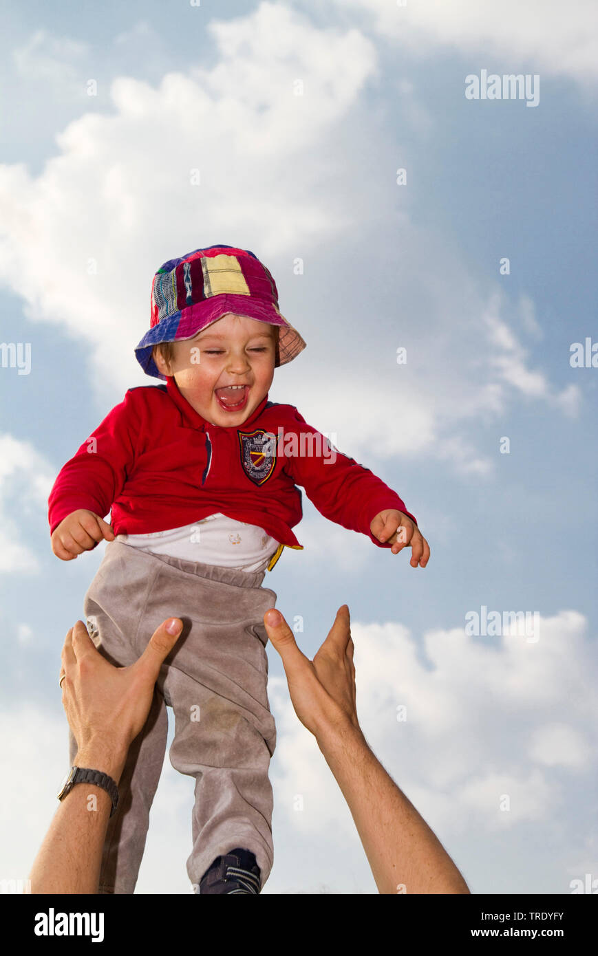 Portrait of a young boy thrown up into the air by an adult Stock Photo