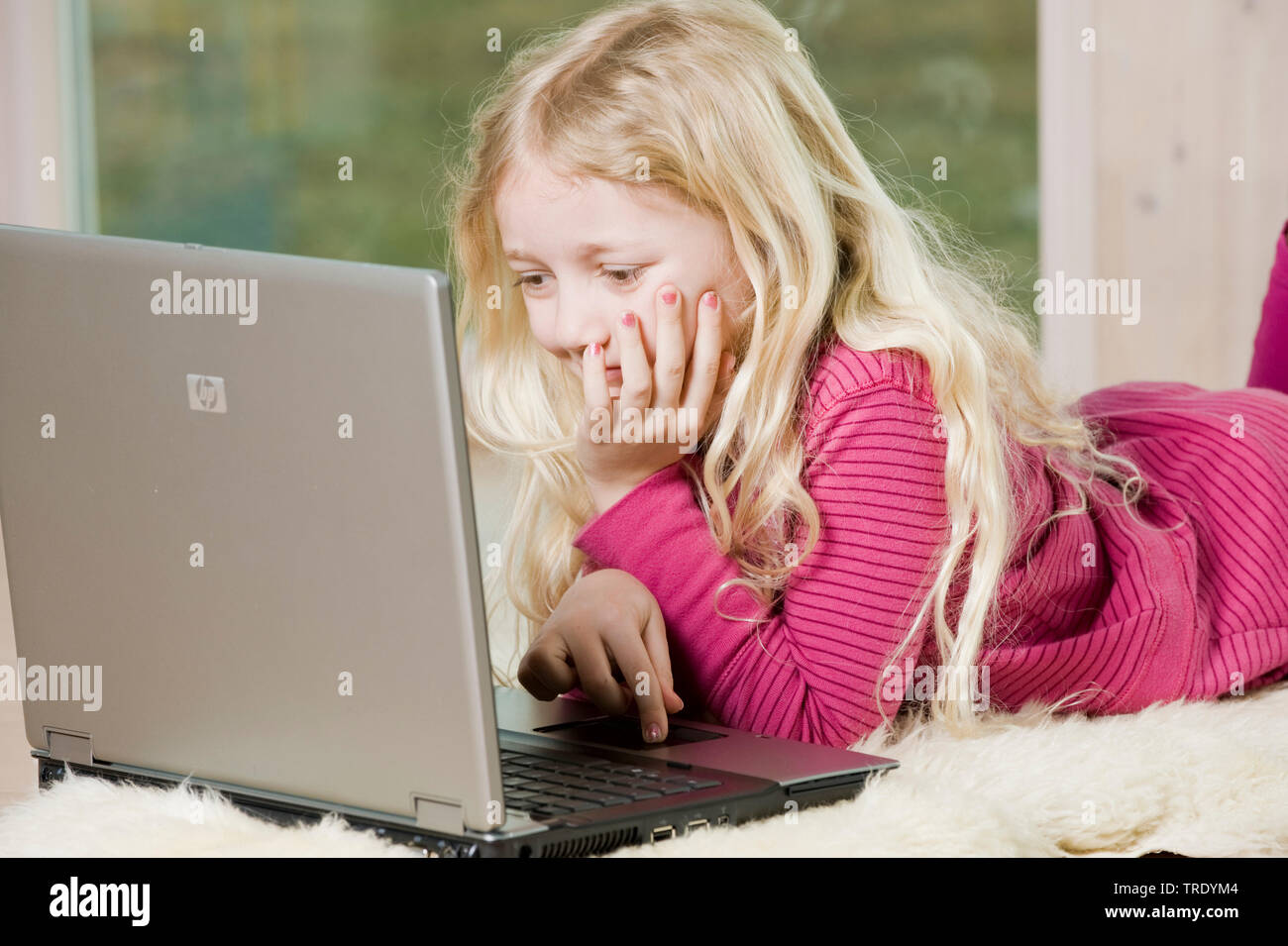 Portrait of a girl lying on the floor and playing with a laptop Stock ...
