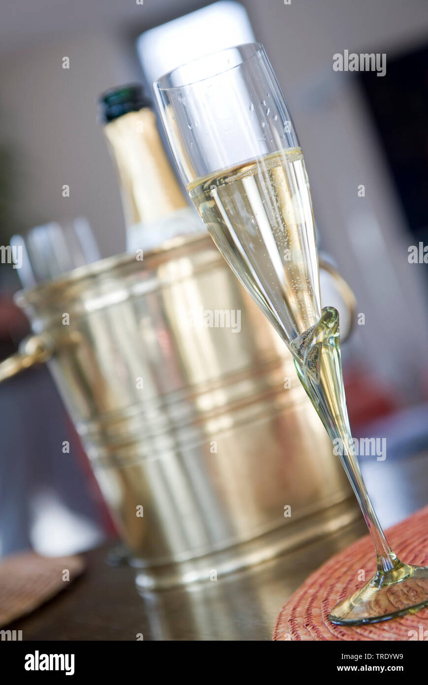 Half-full champagner glass in front of a champagne bottle in a bottle chiller Stock Photo