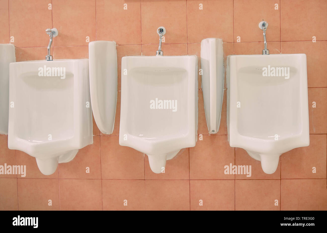 Row of urinal toilet blocks for man in tiled wall in public toilet