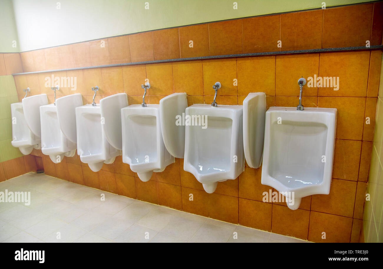 Row of urinal toilet blocks for man in tiled wall in public toilet
