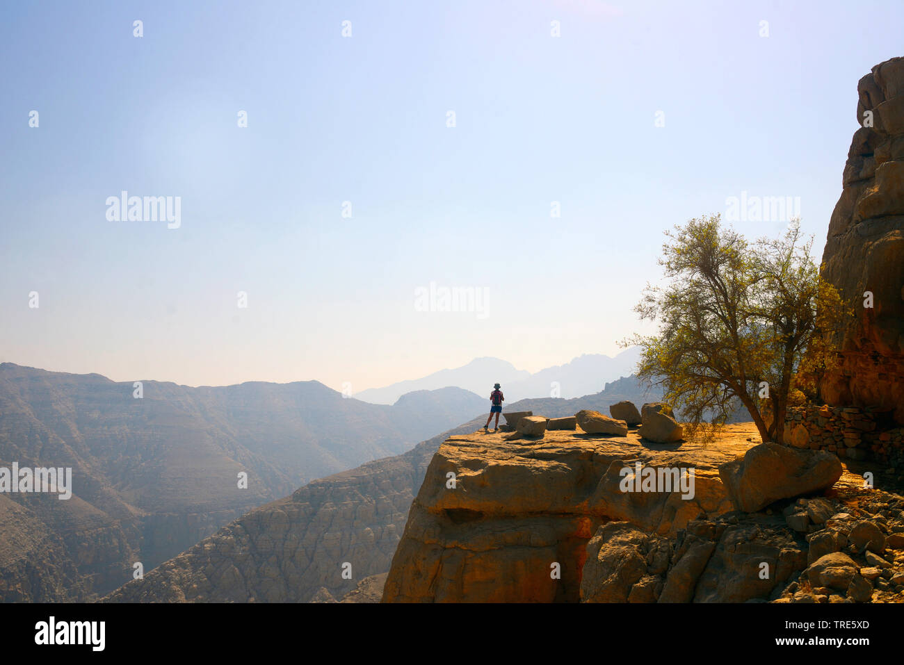 female wanderer standing on rocky plateau and enjoying the view, Oman, Musandam, Khasab Stock Photo