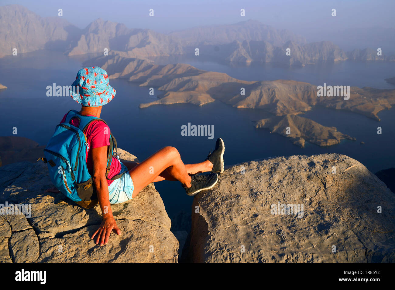 female wanderer enjoying the view from a high mountain to the Bay of Sham, Oman, Khasab Stock Photo