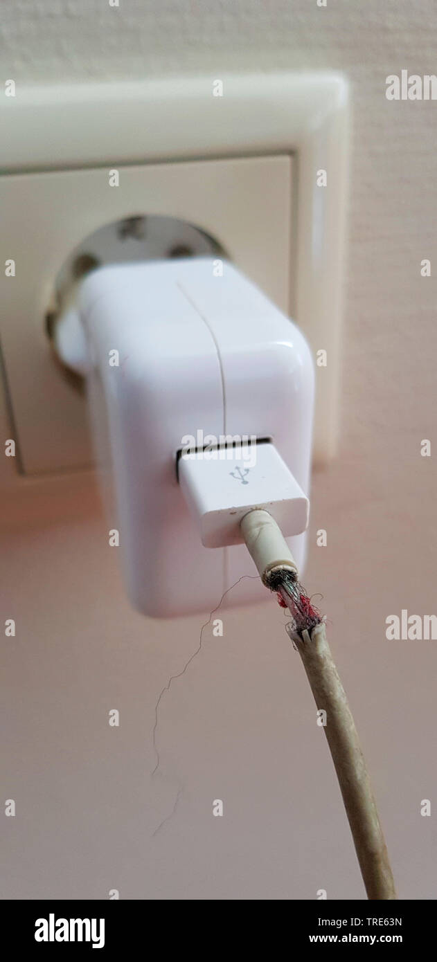 damaged charging cable at a socket, Germany Stock Photo