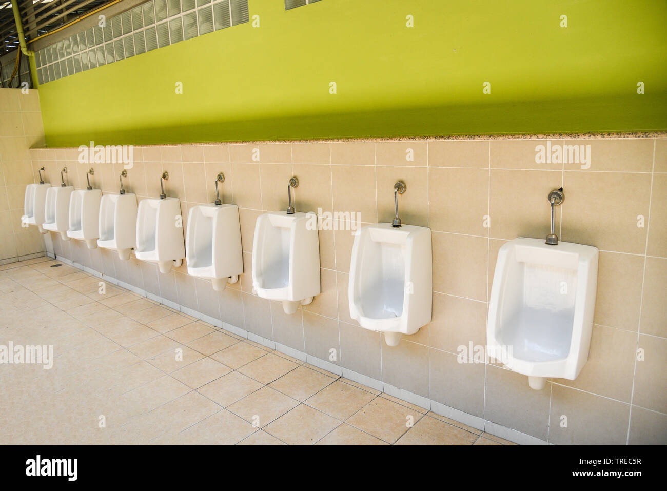 Row of urinal toilet blocks for man on tiled wall in public toilet