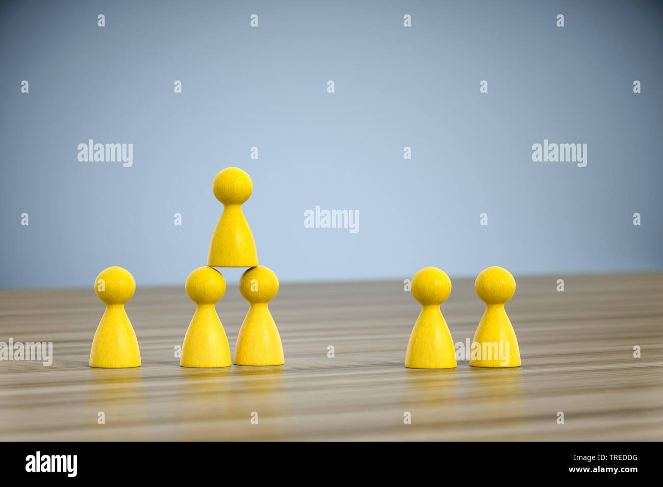 Number of yellow pawns building a pyramid - teamwork Stock Photo