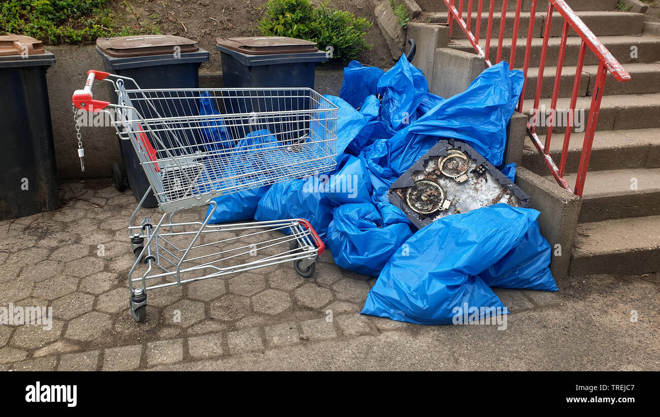 stolen shopping cart and garbage bags in front of organic waste bins, Germany Stock Photo