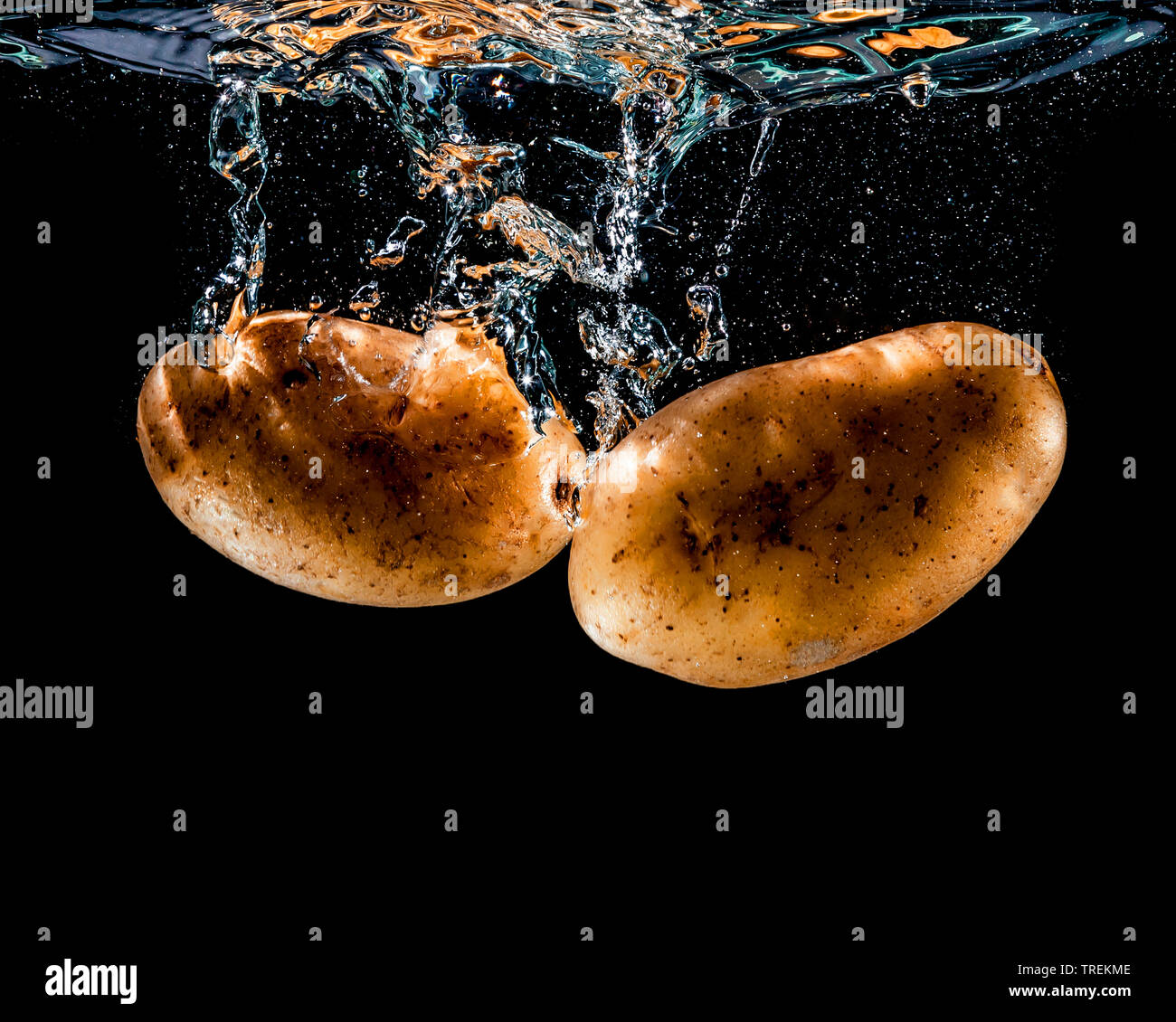 potato (Solanum tuberosum), two potatoes falling into the water Stock Photo