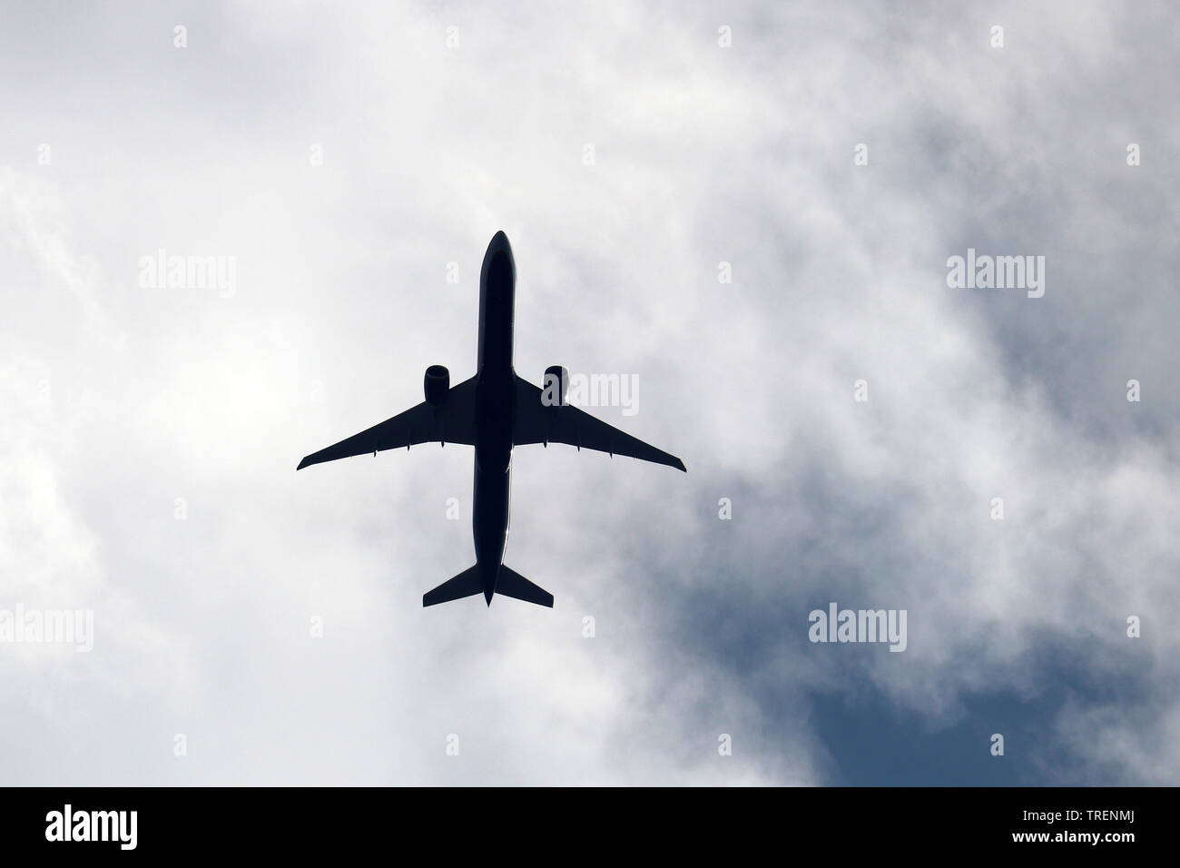 Airplane silhouette in the sky close up. Commercial plane taking off on background of white clouds Stock Photo