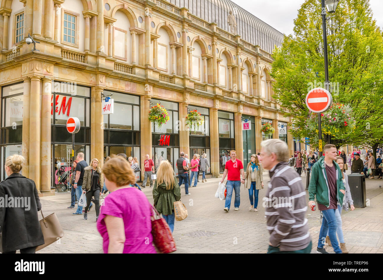 Locals and Tourists strolling around pedestrian zone lined with shops and restaurants in Harrogate  city centre, Yorkshire, UK. on a cloudy autumn day. Stock Photo