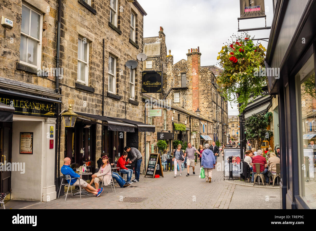 People enjoying a warm Autumn day in a cobbled Street lined with Restaurant and Shops in Harrogate, England, UK. Stock Photo
