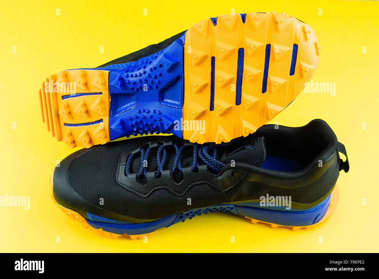 black sneaker with orange insert, mesh fabric, on a yellow background, running and fitness sneakers on yellow background Stock Photo