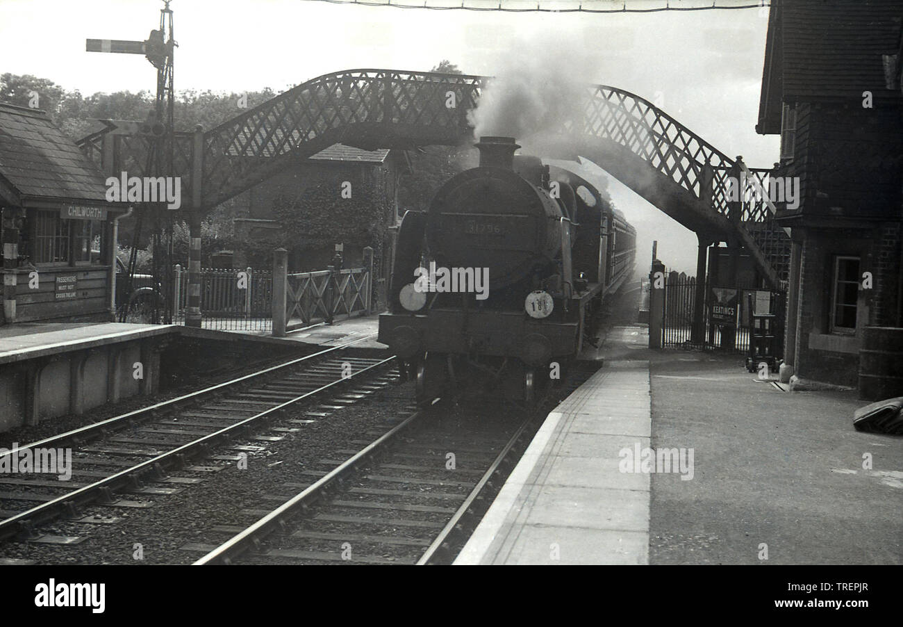 1950, historical, a steam train coming into the railway station, of Chiworth village, near Guildford, Surrey, England, UK. The number on the front of the British Railways steam locomotive is 31796. The train station began operations in 1849  and was originally known as Chilworth and Albury, incorporating the nearby village of Albury. At this time, the historic old footbridge and crossing gates were still in use. Stock Photo
