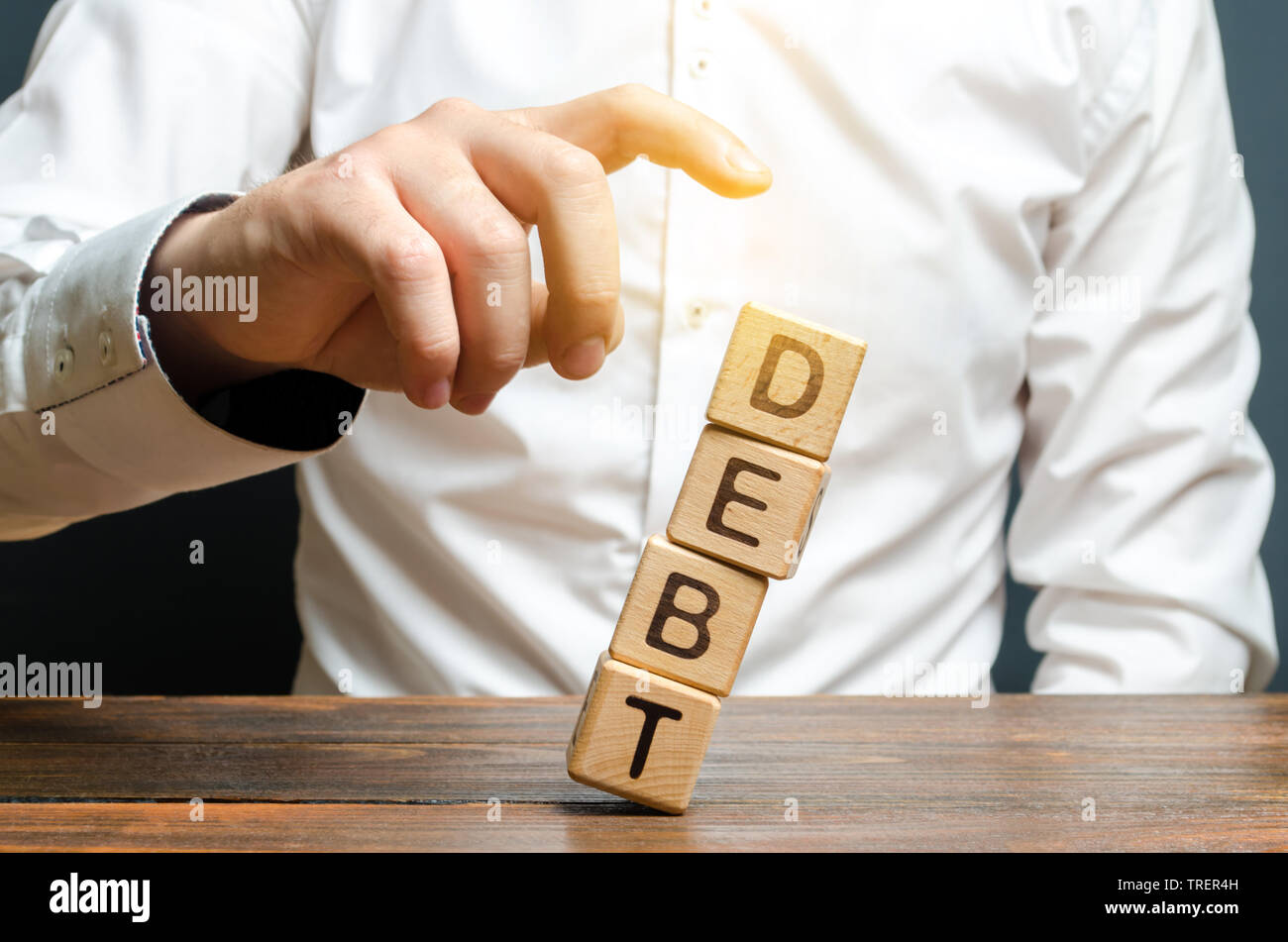 A businessman pushes down a tower of cubes with the word Debt. concept of financial relief, loan restructuring. Financial stability and independence. Stock Photo