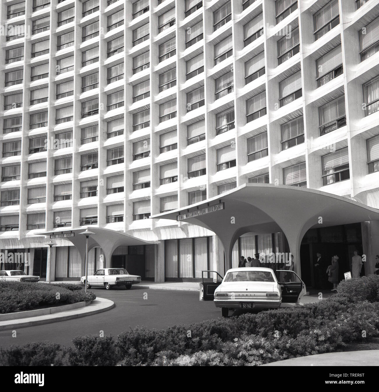 1960s, historical, exterior of The Washington Hilton Hotel,  showing guests at the canopied entrance, Washington, DC, USA.  A Comet American car is parked outside. Beside the hotel is The Four Oaks apartments, so named as the hotel was built on the former Oak Lawn estate. The 60s and 70s saw a number of big music concerts held in the large ballroom. In 1981 it was the site of an assassination attempt on the life of President Ronald Reagan, Stock Photo