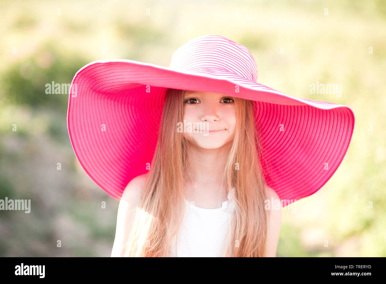 Funny smiling kid girl 4 5 year old wearing big pink hat outdoors. Looking at camera. Childhood Stock Photo Alamy