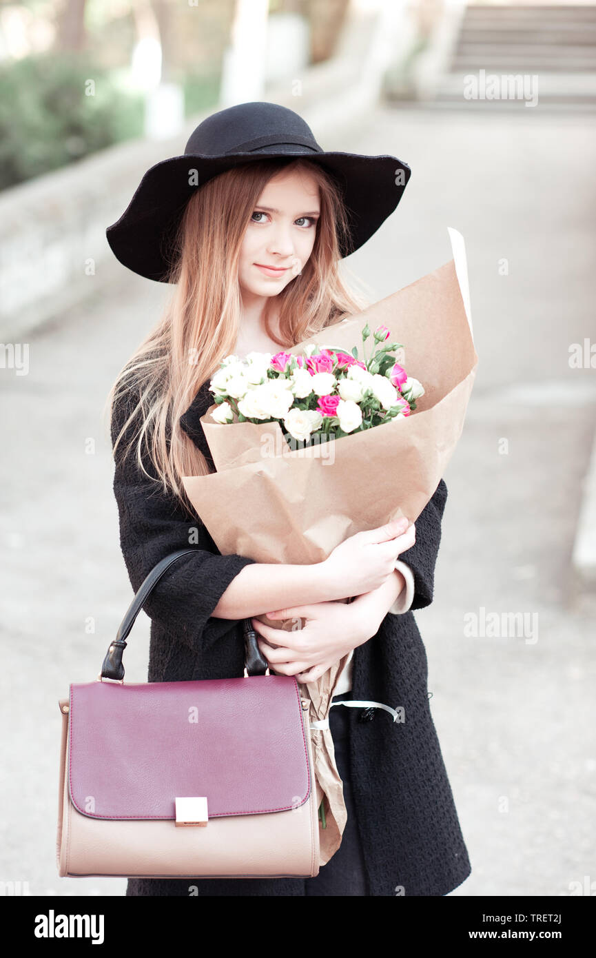 Beautiful teen girl 14-15 year old wearing stylish clothes sitting  outdoors. Looking at camera. Autumn season. Stock Photo