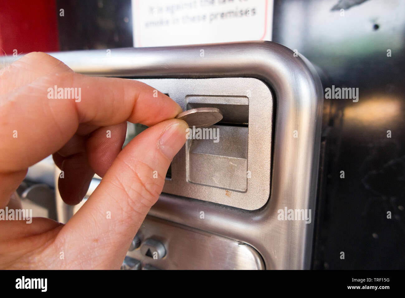 Person pushing a 20p coin into the slot of a late model coin operated