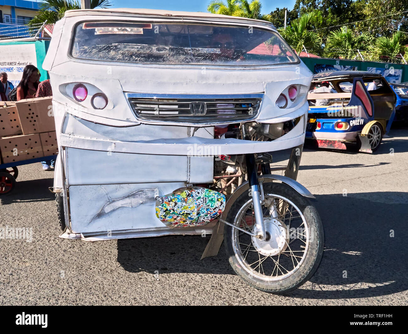 Puerto Princesa City, Palawan, Philippines: White cabin tricycle with driver looking for passengers in the city streets Stock Photo