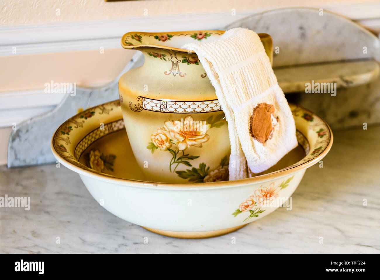 Old fashioned ceramic washbowl and jug with a facecloth. Stock Photo