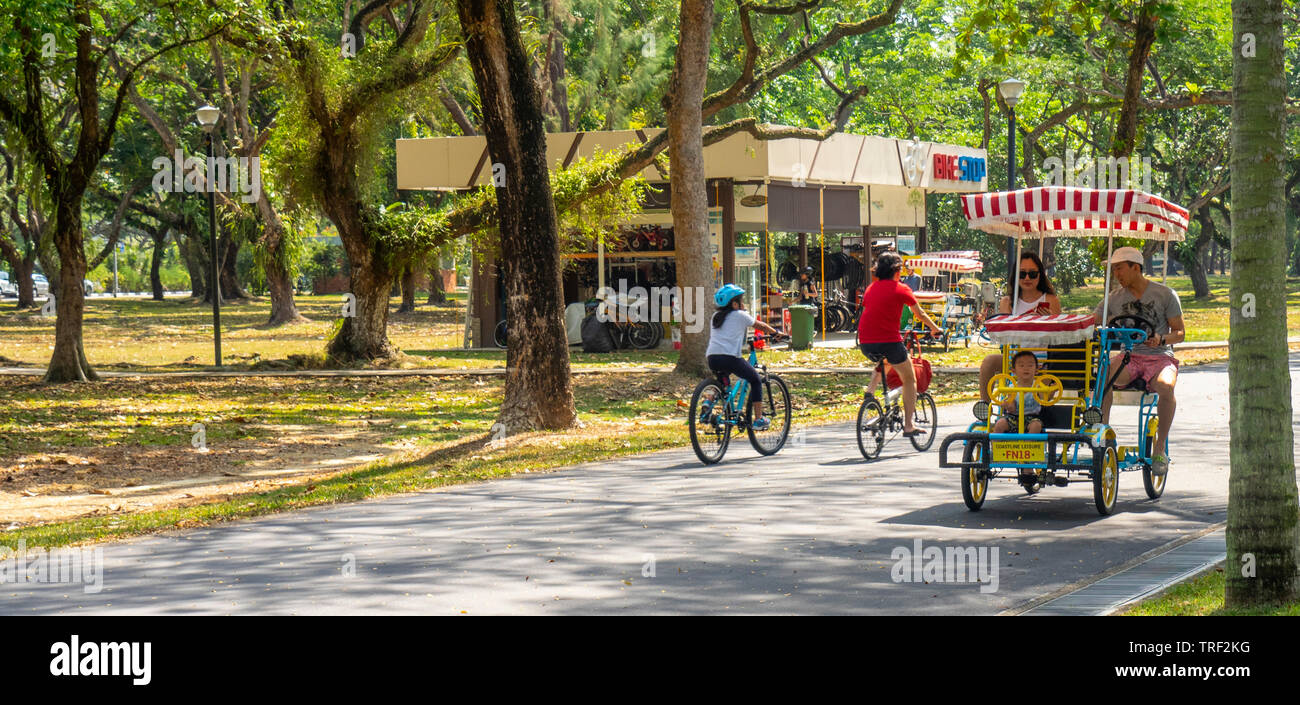 A family riding a quad cycle along East Coast Park Singapore Stock